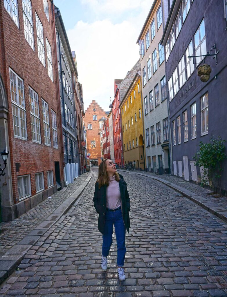 A young woman studying abroad walks down a historic street 